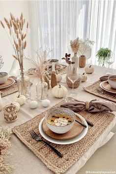 the table is set with plates, bowls and vases