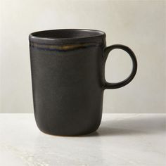 a black coffee cup sitting on top of a white counter