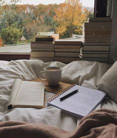 a cup of coffee, notebook and pen on a bed