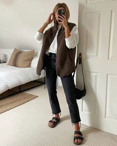 blond woman wearing black pants, sandals, white jumper, and brown vest. She is taking a selfie. Minimal Sweater Outfit, Vivian Audi Fall Outfits, Work Birkenstock Outfit, 90s Mom Style Outfit, Causal Trousers Outfit, White Summer Suits Women, Cute Casual Sneaker Outfits, Luxe Leisure Style, Long Waisted Outfits