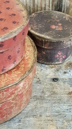 three old tins are stacked on top of each other, one is red and the other is brown