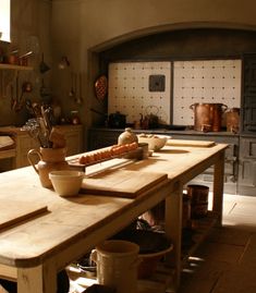 an old fashioned kitchen with many pots and pans on the counter top in front of it