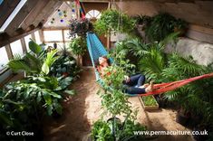 a woman laying in a hammock surrounded by plants