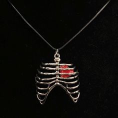 Please read descriptions thoroughly for sizes and materials.  This is a silver metal pendant featuring a silver metal rib cage, through which you can see a red heart. It's hung from a waxed black cord that is 19 1/2" long, with silver chain and a silver lobster claw clasp. * Also available on a 18", 20", 24", 28" or 30" silver stainless steel snake chain.  The pendant is 2" X 2". Make sure to check out my shop for more hair pins, jewelry, accessories, and all sorts of fun stuff! Please note: I am not responsible for any items lost or damaged in the mail. Please double check your address before ordering, and I recommend purchasing insurance. Skeleton Ribs, Silver Rib Cage, Red Heart, Skeleton Necklace, Halloween Jewelry, Silver Skeleton, Body Parts, Skeleton Jewelry Skeleton Body Parts, Skeleton Ribs, Heart Skeleton, Skeleton Body, Skeleton Jewelry, Skeleton Necklace, Parties Du Corps, Halloween Jewelry, Rib Cage