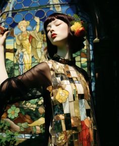 a woman standing in front of a stained glass window with her hand on her hip