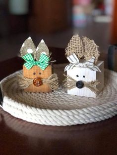 two small wooden reindeers are sitting on a roped tray with twine and burlap