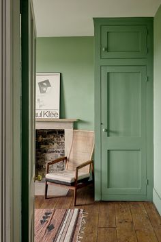 a chair sitting in front of a green door next to a rug on the floor