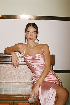 a woman in a pink dress sitting on top of a dresser