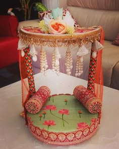 an elaborately decorated chair sits on a table in front of a couch and flower arrangement