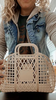 a woman holding a white purse on top of a table