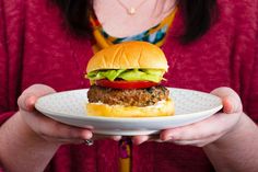 a woman holding a plate with a hamburger on it