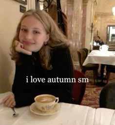 a woman sitting at a table with a cup and saucer in front of her