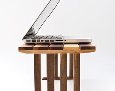 an open laptop computer sitting on top of a wooden table next to a white wall