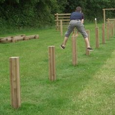 a man jumping over some wooden posts in the grass