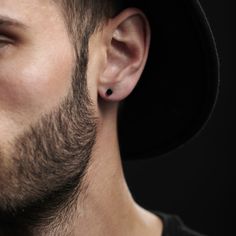 a man wearing a black hat and ear piercings