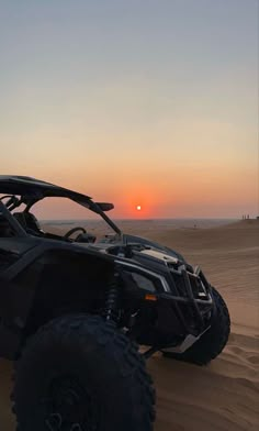 the sun is setting in the distance behind a four - doored vehicle on sand dunes