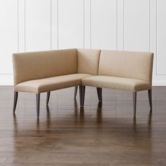 a corner couch sitting on top of a hard wood floor next to a white wall