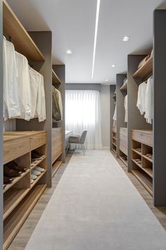 a large walk in closet with lots of wooden shelves and clothes hanging on the walls