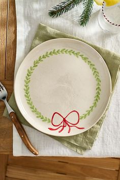 a white plate with a red bow on it sitting next to a knife and fork