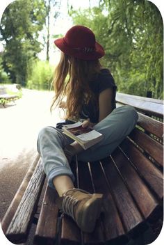 a woman sitting on top of a wooden bench