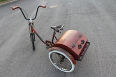 an old bicycle with a wooden seat is parked on the side of the road next to a bike rack