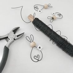 a pair of pliers and some wire on a table with paper clips in the shape of rabbits