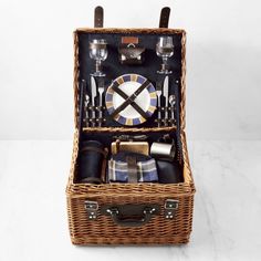 a wicker picnic basket filled with silverware and napkins on a white table