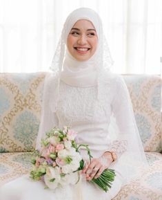 a woman sitting on top of a couch holding a bouquet