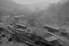 an old black and white photo of a town in the mountains with buildings on it