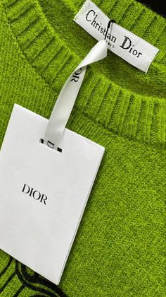 a green sweater with a tag attached to the front and back of it that says christian dior