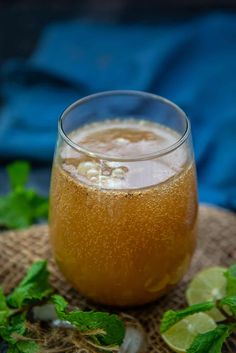 a glass filled with liquid sitting on top of a table next to some mint leaves