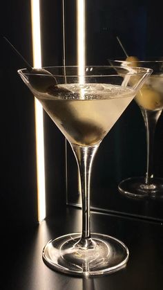 two martini glasses sitting next to each other on a table