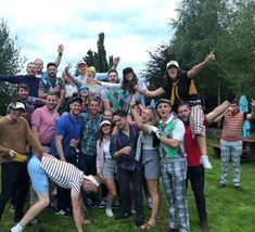 a group of people standing on top of a lush green field next to each other