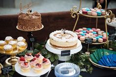 a table topped with cakes and cupcakes next to other desserts on plates