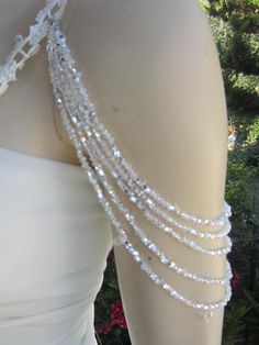 the back of a woman's white dress with beads on it