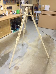 a large wooden easel in a garage with tools on the table and shelves behind it