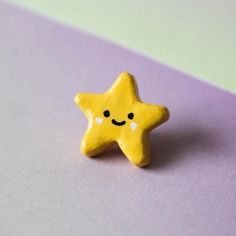 a small yellow star with a smiley face on it's side sitting on a purple and green surface