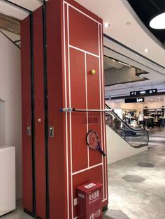 a tennis racket is on display in the store's entrance area, with an escalator behind it