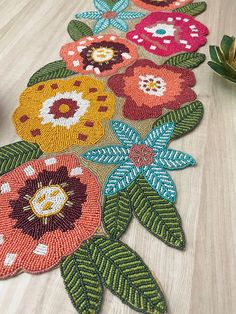 an image of flowers on the floor that is made out of beadwork and yarn