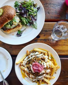 two plates with food on them sitting on a table next to glasses and silverware