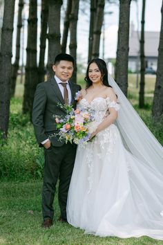 a bride and groom pose for a photo in front of the trees at their wedding