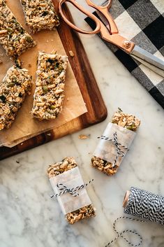 homemade granola bars sitting on top of a cutting board next to scissors and other items