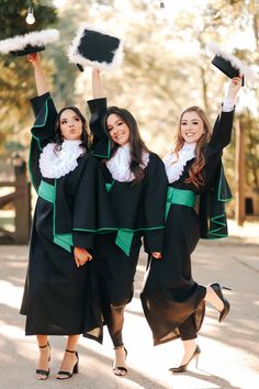 three women in graduation gowns holding up their hats