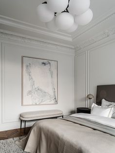 a bedroom with a bed, bench and painting on the wall above it's headboard