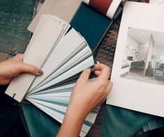 a person is holding some paint samples in their hands and looking at the color swatches