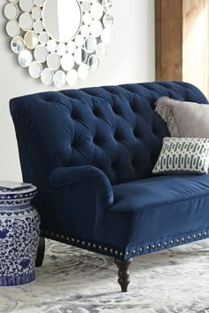 a blue couch sitting on top of a rug in a living room next to a mirror