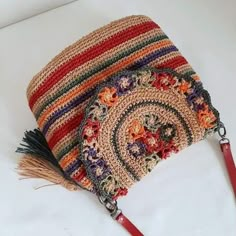 a crocheted purse with a tasseled handle on a white table top