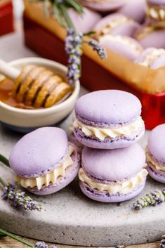 lavender macaroons are stacked on top of each other with honey in the background