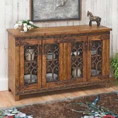 a wooden sideboard with glass doors on top and a horse figurine sitting on top