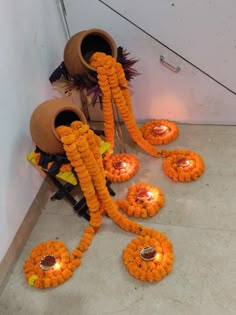 an arrangement of orange flowers and candles on the ground next to a wall with pots